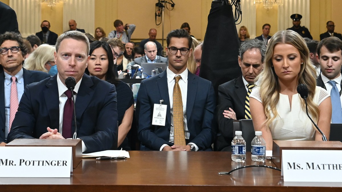 Photo of a man in the crowd who looks like Clark Kent from Superman. He is wearing a suit and tie and glasses.