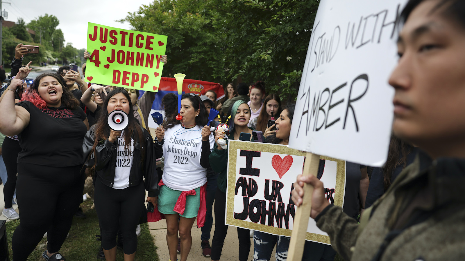 Johnny Depp supporters holding up signs and megaphones while argue with an Amber Heard supporters, also holding up signs.