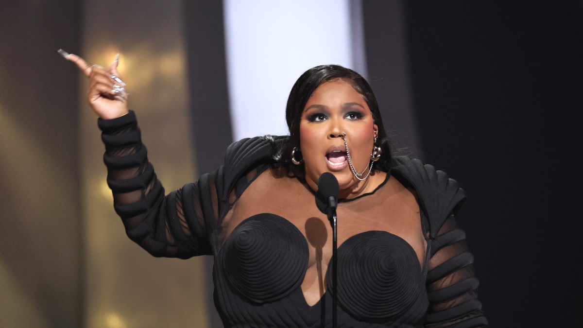 Lizzo accepting a VMA in a black dress