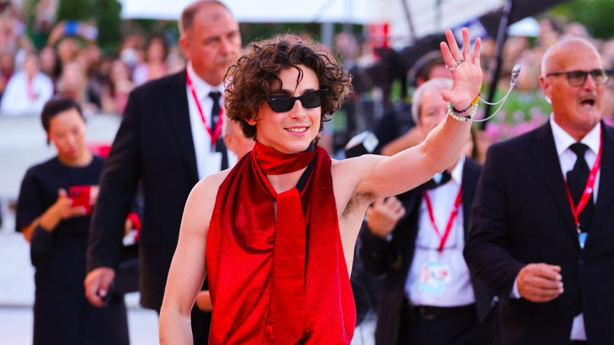 Timothée Chalamet attends the "Bones And All" red carpet at the 79th Venice International Film Festival on September 02, 2022 in Venice, Italy wearing a blood red sleeveless jumpsuit and waving at his fans