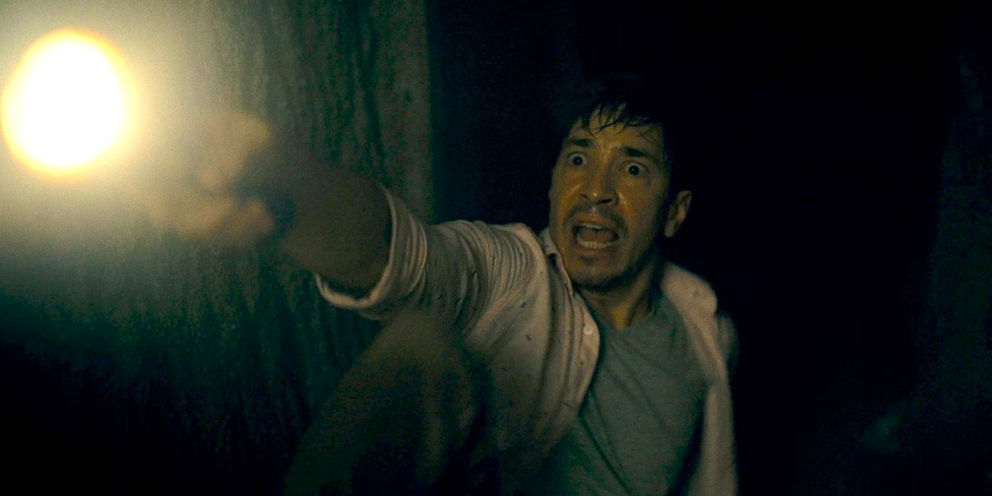A man looks terrified as he holds up a flashlight in Barbarian. 