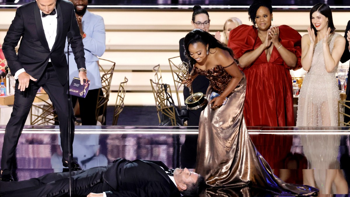 Quinta Brunson (R) accepts Outstanding Writing for a Comedy Series for "Abbott Elementary" from Will Arnett (L) while Jimmy Kimmel lies onstage during the 74th Primetime Emmys at Microsoft Theater on September 12, 2022 in Los Angeles, California.