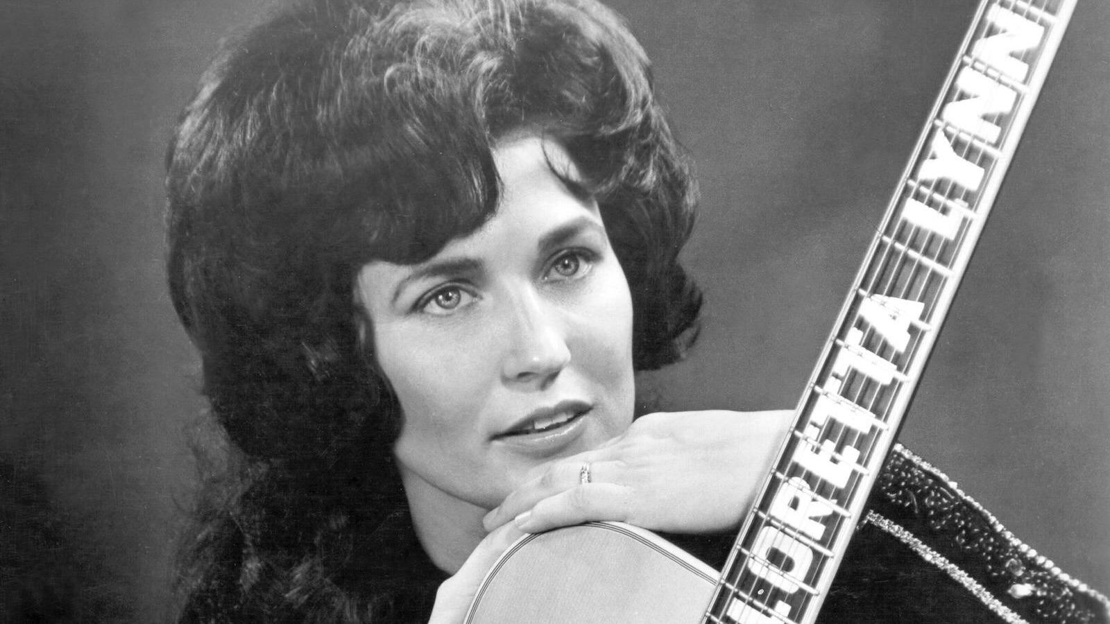 Loretta Lynn poses for a portrait holding a guitar that has her name spelled down the fretboard in circa 1961 in Nashville, Tennessee.