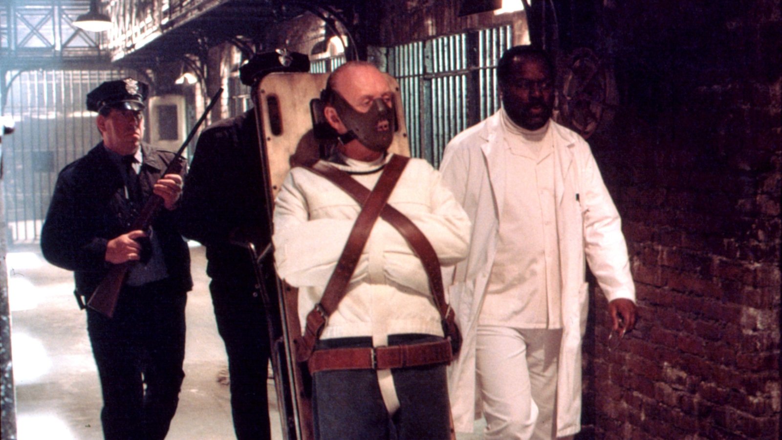 Anthony Hopkins as Hannibal Lecter being wheeled on an upright stretcher surrounded by prison guards