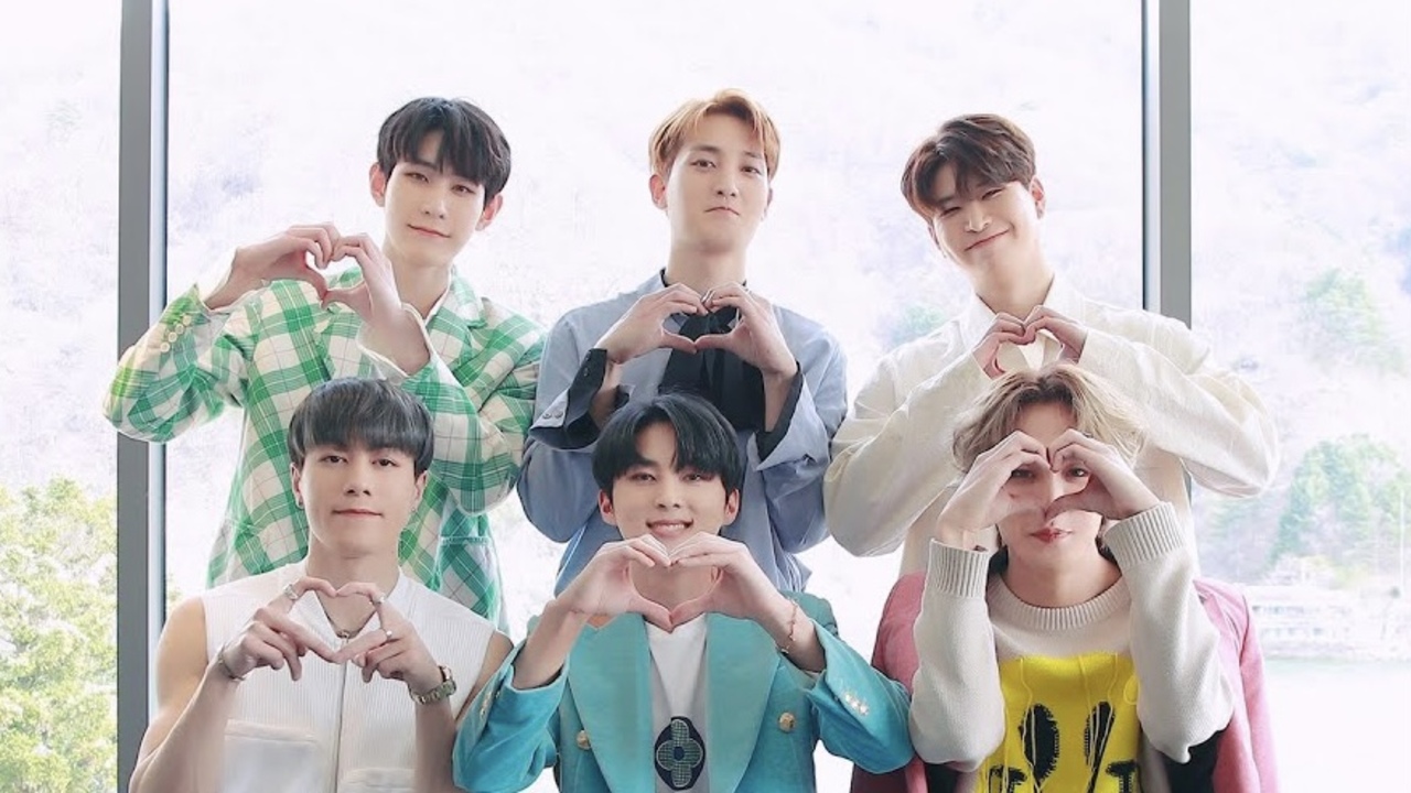 A group of K-pop singers making heart signs and smiling.