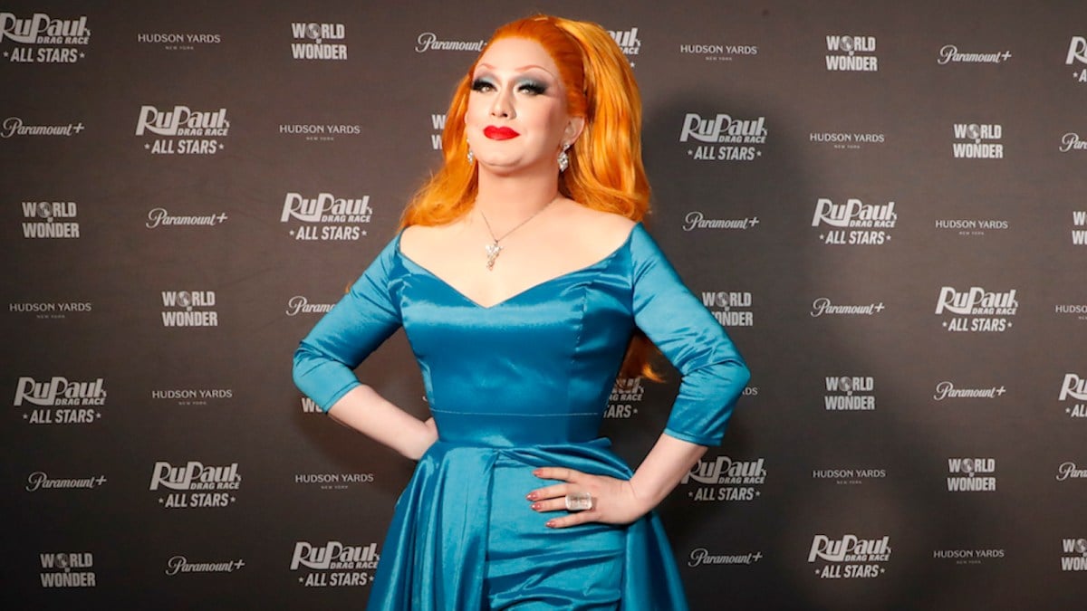 Jinkx Monsoon wearing a teal dress and signature red wig on the red carpet