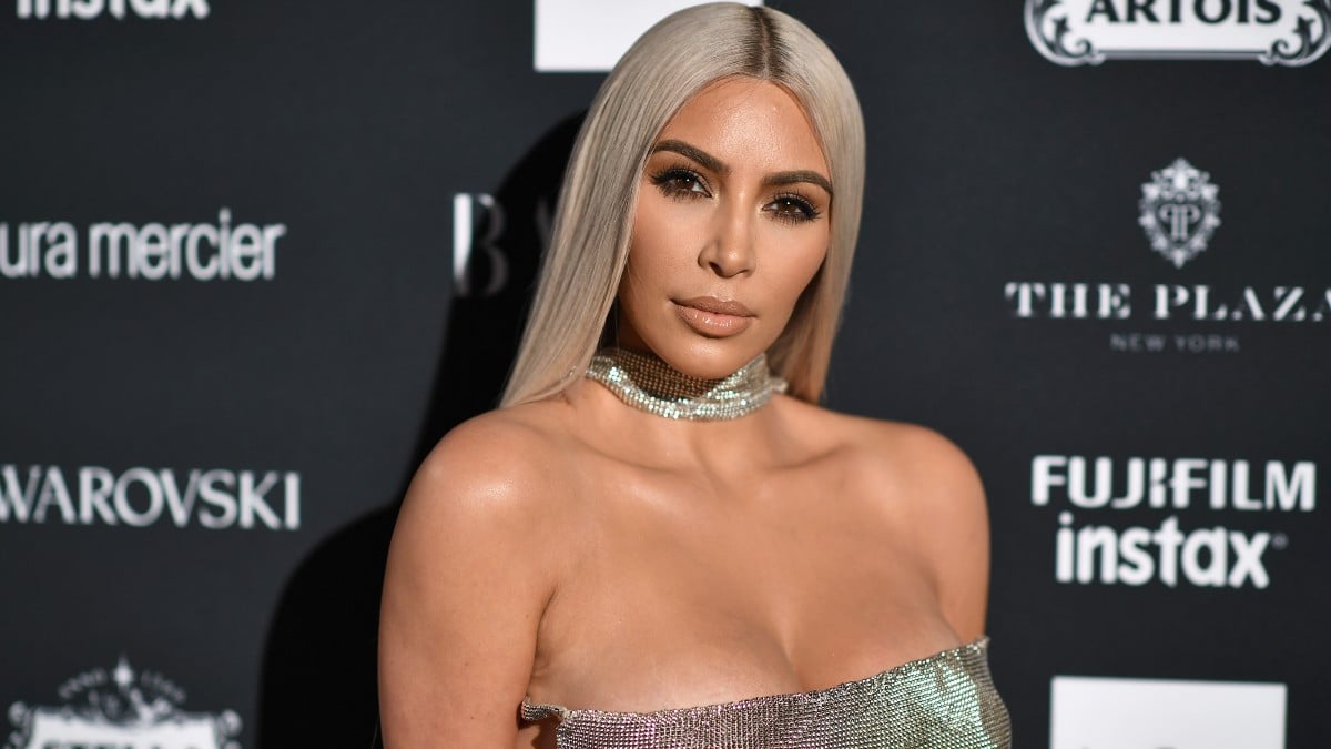 Kim Kardashian is standing on the red carpet with blonde hair.