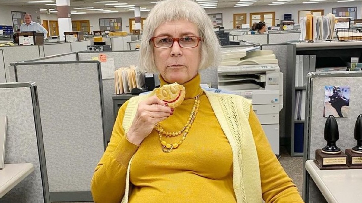 Jamie Lee Curtis eating a cookie in a yellow turtleneck