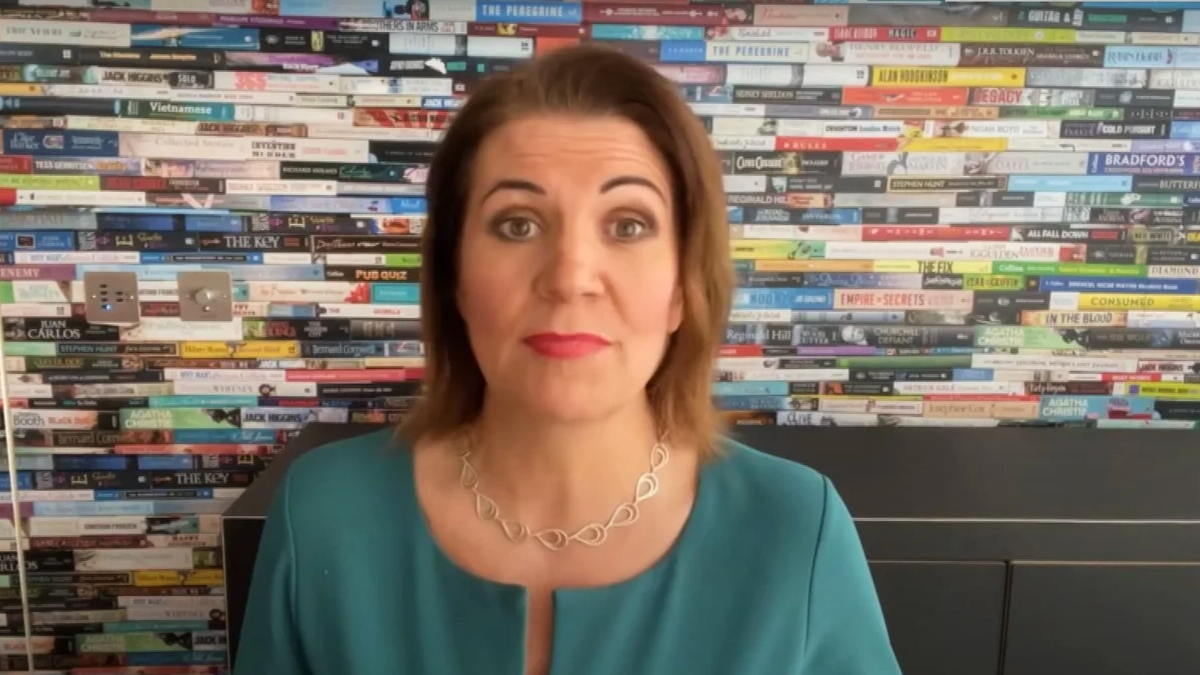 Julia Hartley-Brewer is sitting in front of a wall with books.