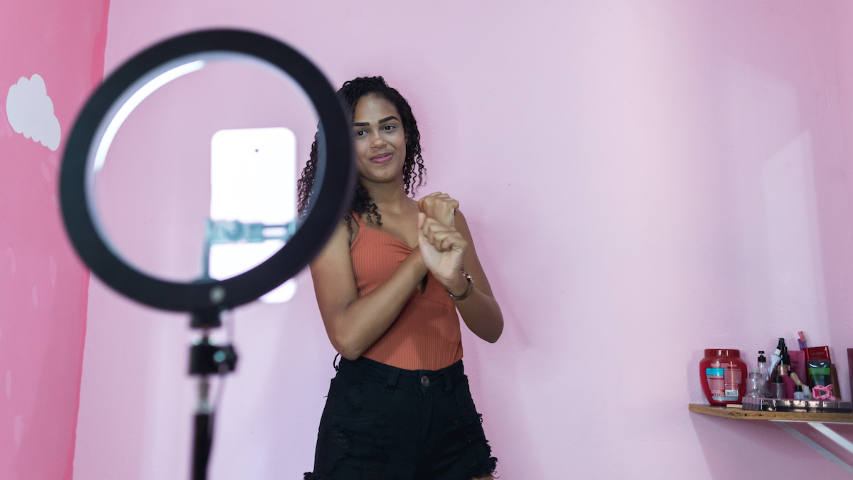 Black young woman filming herself dancing at home to share on social media