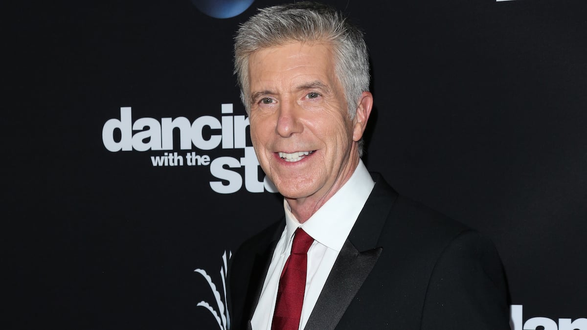 TV Host Tom Bergeron attends ABC's "Dancing With The Stars" season 23 finale at The Grove, waring a black suit, white shirt, and red tie