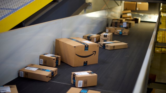 Amazon boxes travel on a conveyer belt at a fulfillment center.