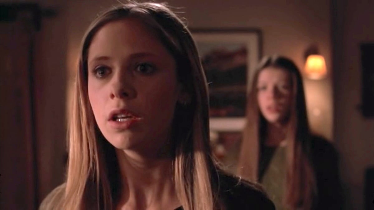 Buffy looking past the camera expectedly with Dawn blurred in the background in the episode "Forever" from 'Buffy the Vampire Slayer'