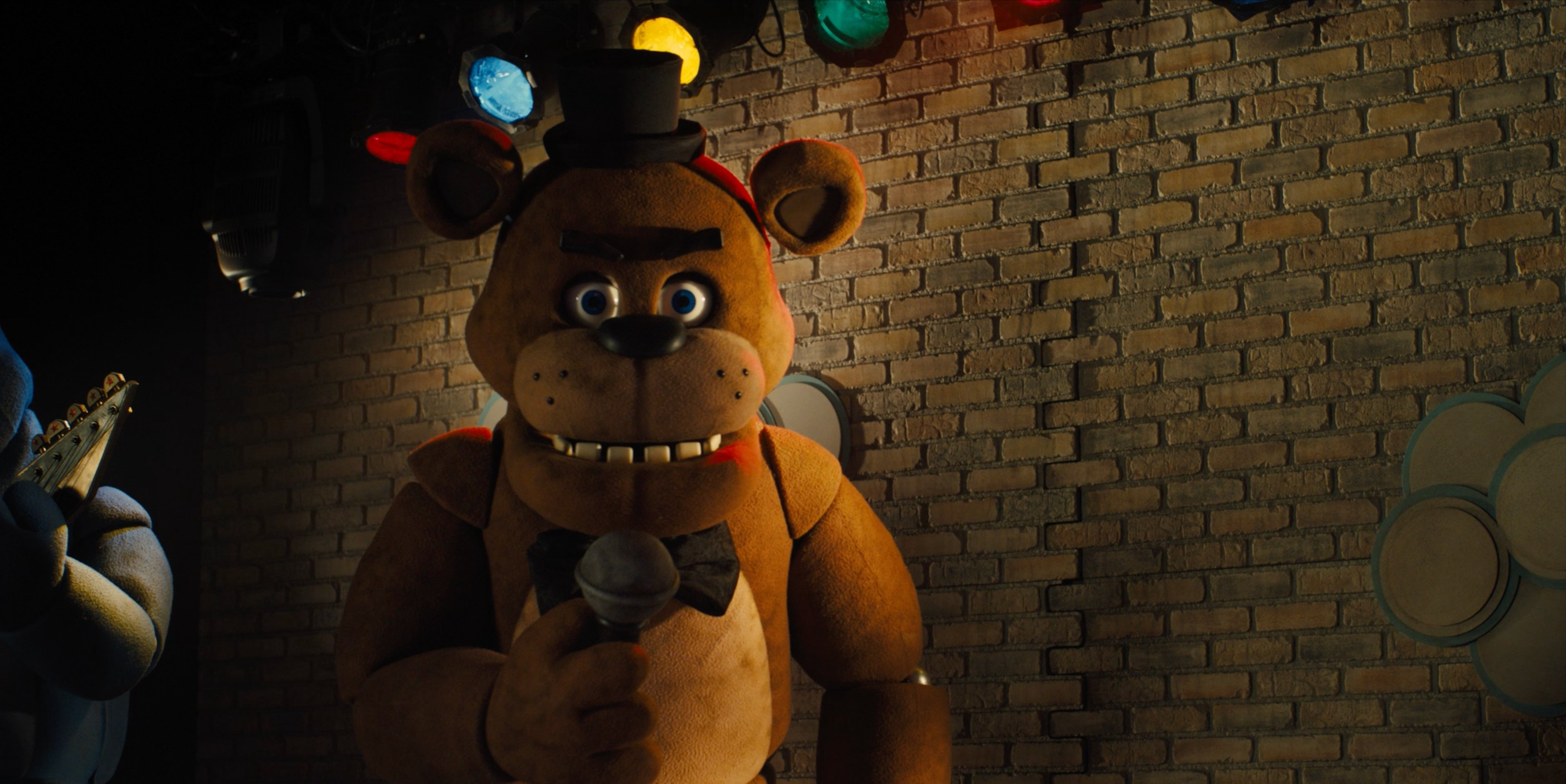 Freddy Fazbear is holding a microphone. 