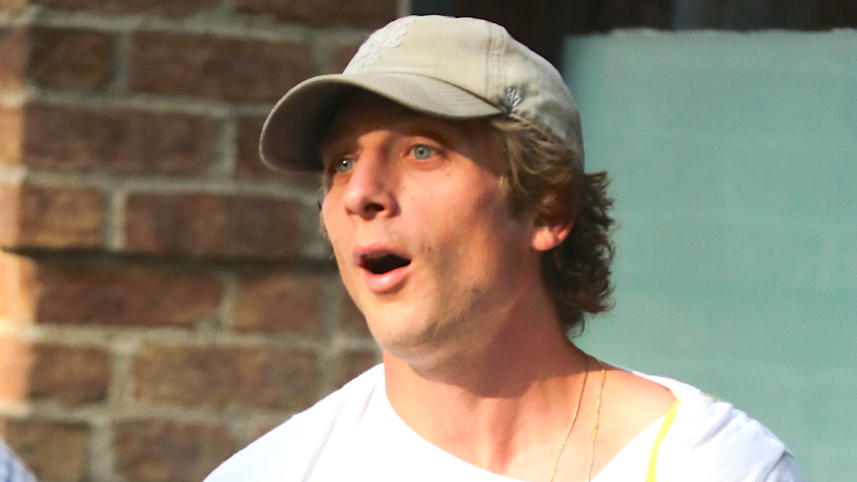 Jeremy Allen White wearing a white T-shirt and a hat in NYC, gasping at something someone said