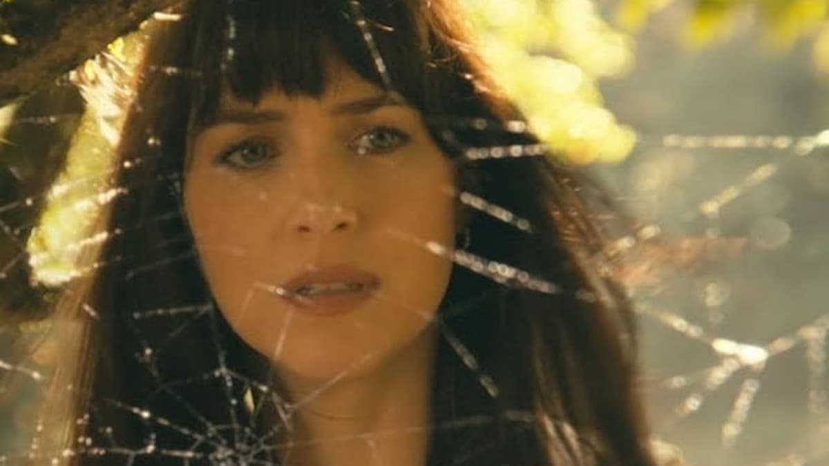 Dakota Johnson's Cassandra Webb looks through a spider's web in Madame Web. 