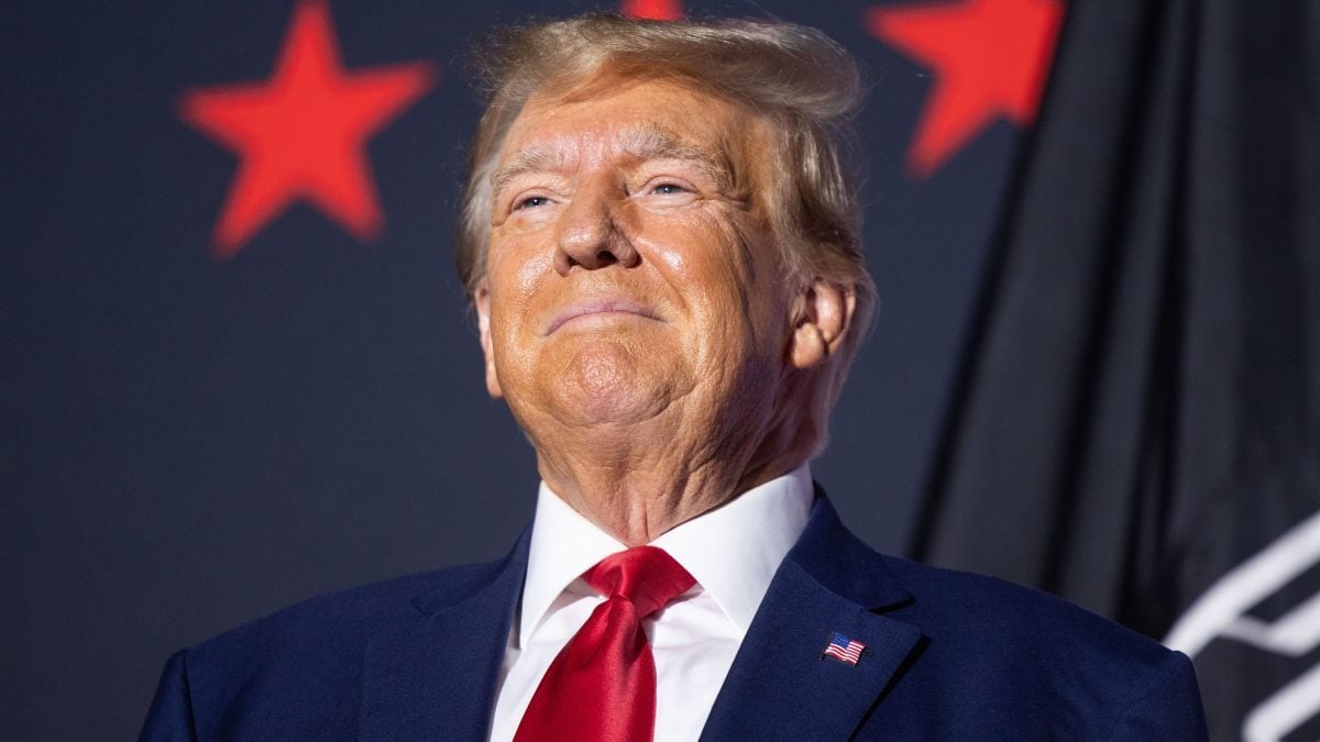 Donald Trump smiling in a blue suit and red tie