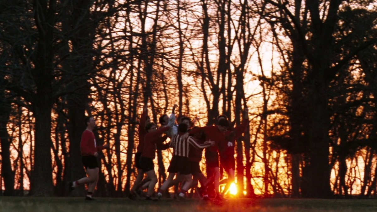 The boys of 'Dead Poet Society' lift Robin Williams with the sunset behind them.