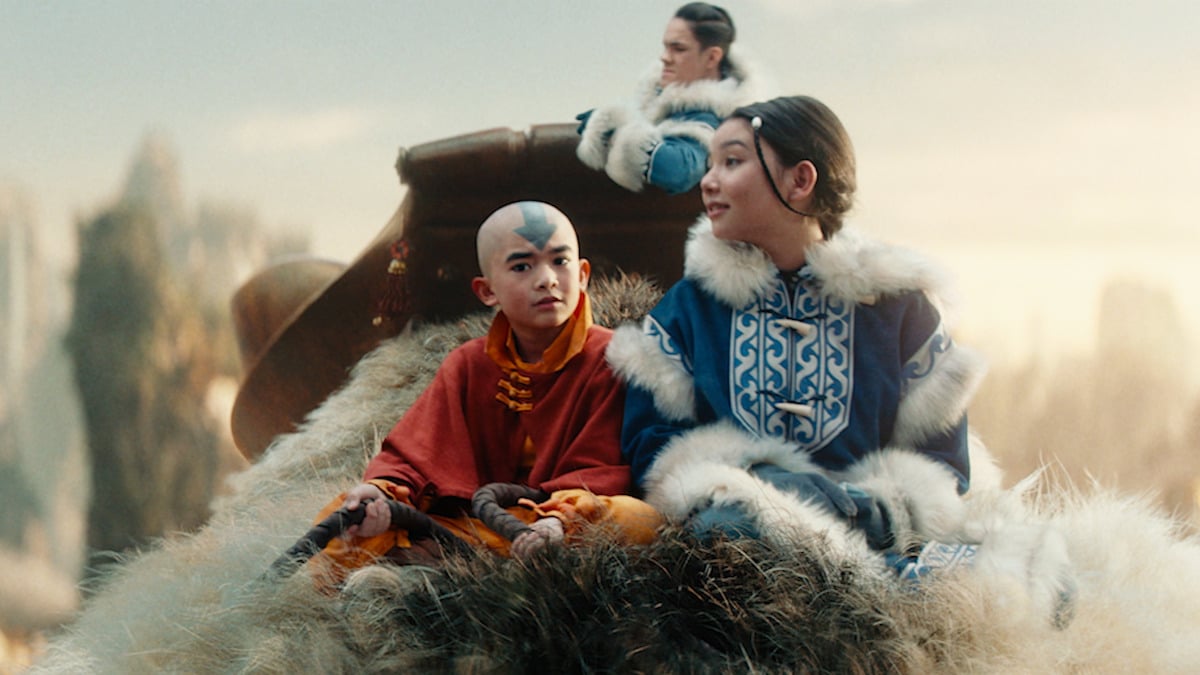 Soka (Ian Ousley), Aang (Gordon Cormier), and Katara (Kiawentiio) ride on the back of Appa in Netflix's Avatar: The Last Airbender