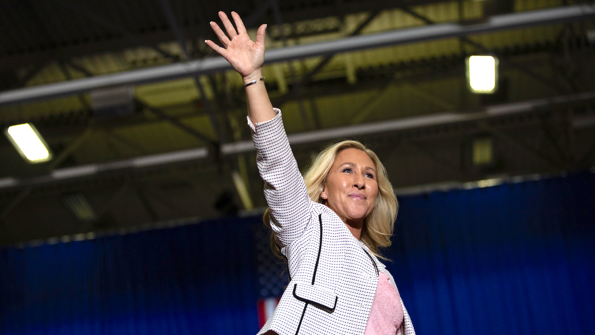 Marjorie Taylor Greene waving to a crowd at a Trump rally