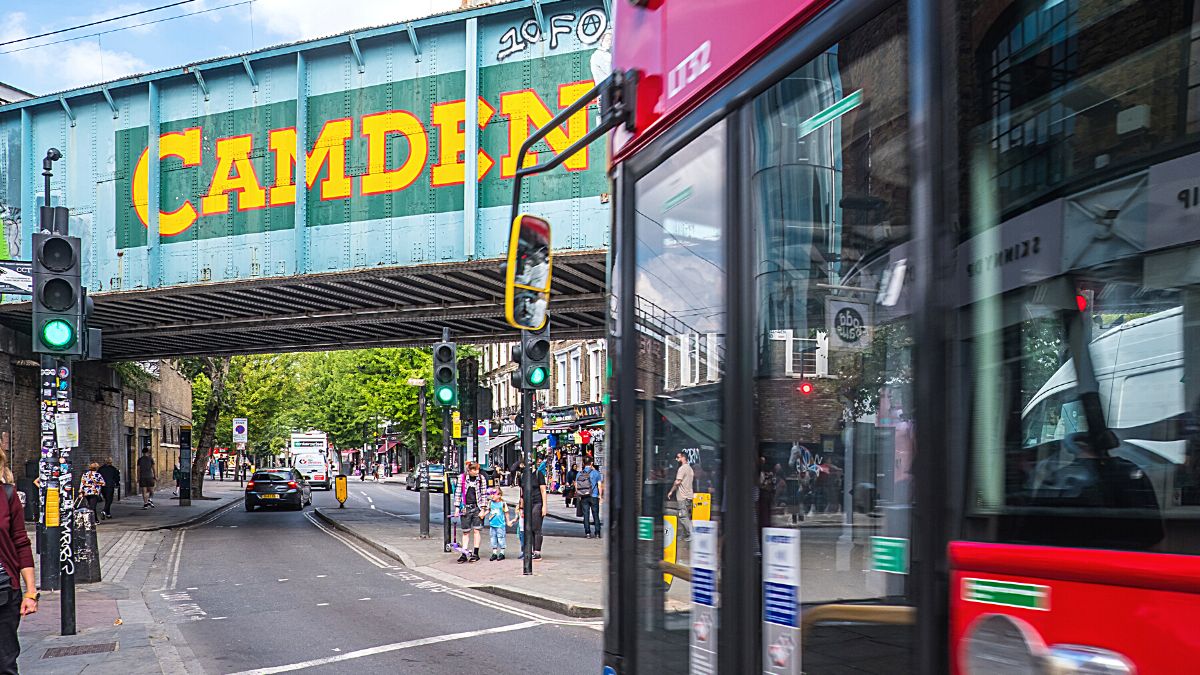 Iconic red double decker bus zooming through the city streets towards the famous Camden Lock bridge in the heart of London, UK.