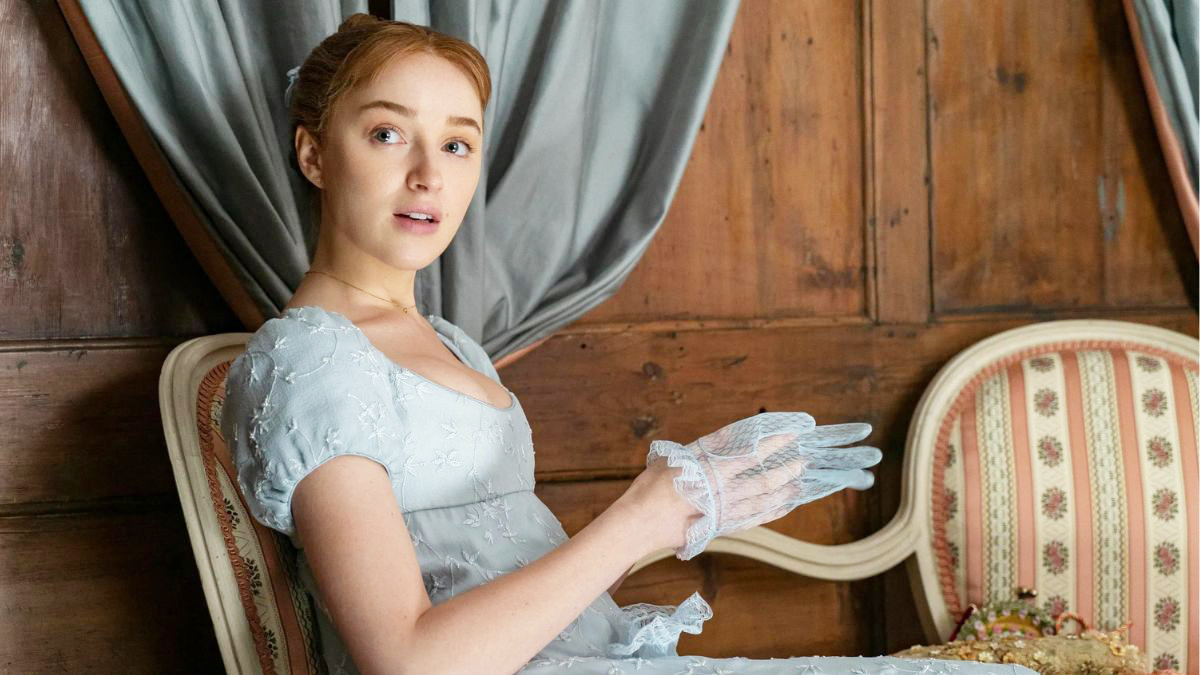 Daphne putting on her gloves while wearing a blue dress in Netflix's Bridgerton