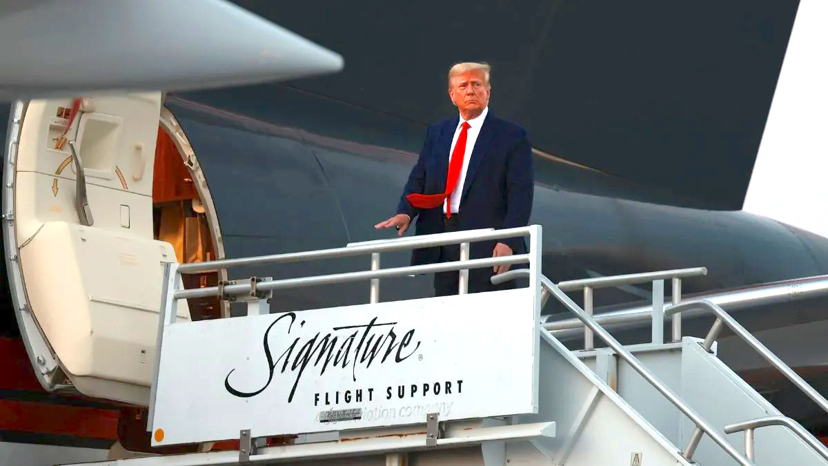 Donald Trump looking smug in a suit as he boards an airplane