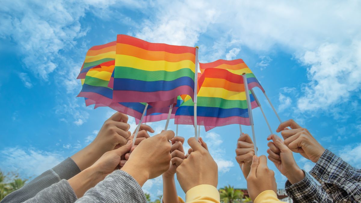 diversity people hands raising colorful lgbtq rainbow flags together , a symbol for the LGBT community ,selective focus.concept LGBTQ community equal movement parade ,LGBTQ pride month.