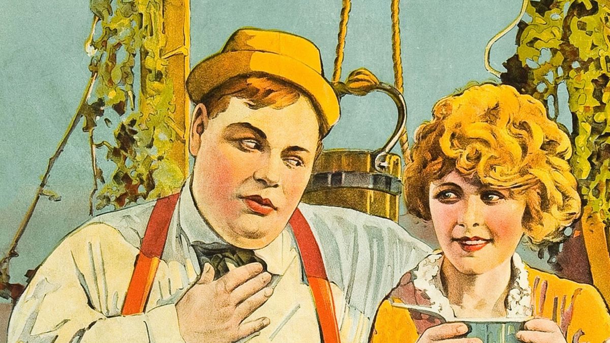 Fatty Arbuckle sits beside a young girl sipping coffee or tea on a poster that advertises the movie 'Love,' 1919. (Photo by Buyenlarge/Getty Images)