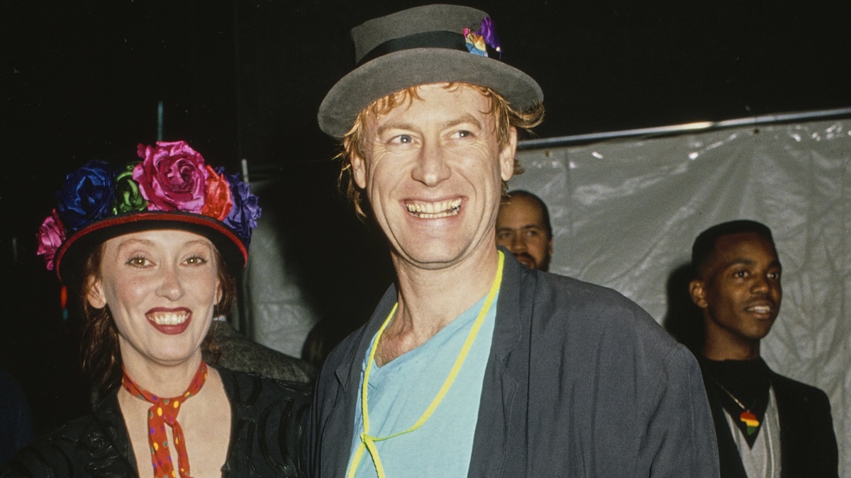 American actress Shelley Duvall, wearing a black jacket with a red neckerchief with multi-coloured polka dots and a floral trimmed hat, and American singer, songwriter and musician Dan Gilroy, who wears a black jacket over a turquoise blue t-shirt with a grey hat